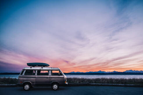 Ein VW Van ist vor dem Puget Sound mit epischem Sonnenuntergang geparkt - CAVF93489