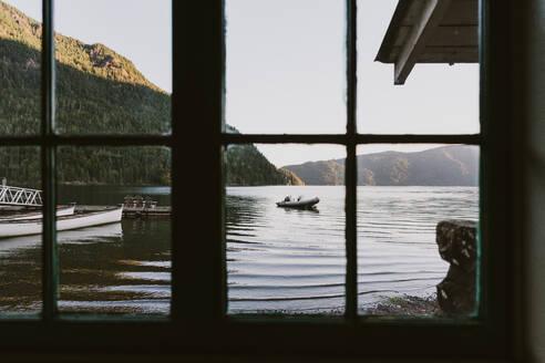 Blick auf den See und das Boot aus dem Fenster der rustikalen Hütte am frühen Morgen - CAVF93515
