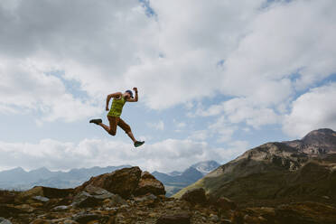 A man jumps into the air in front of mountain landscape - CAVF93532