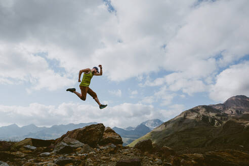 Ein Mann springt vor einer Berglandschaft in die Luft - CAVF93532