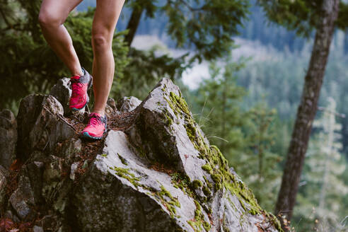 Die Beine einer Frau sind beim Laufen über scharfe Felsen in den Bergen zu sehen - CAVF93537