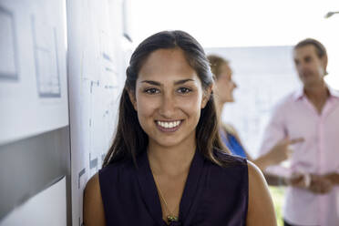 Smiling female architect standing by white board in office - BMOF00509