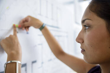 Focused female architect working with graph on white board in office - BMOF00510