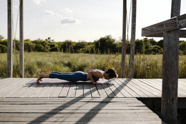 Frau in Sportkleidung macht Yoga am Pavillon - AMPF00055