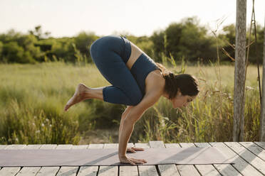 Mid erwachsene Frau tun Handstand Yoga Position am Pavillon - AMPF00065