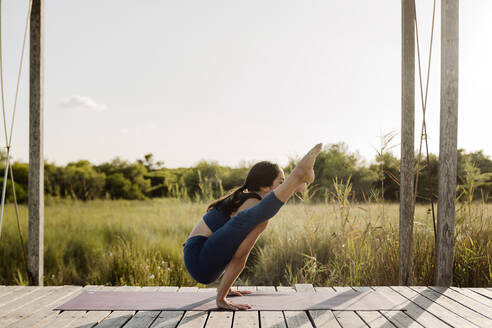 Starke Frau macht Tittibhasana Yoga-Pose am Pavillon - AMPF00066