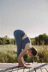 Frau beugt sich in Yoga-Pose am Pavillon - AMPF00067