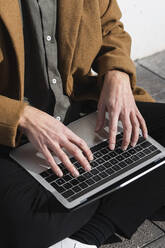 Businessman wearing jacket working on laptop while sitting outdoors - PNAF00826