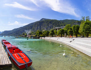 Österreich, Salzburg, Sankt Gilgen, Motorboote am Ufer des Wolfgangsees im Sommer mit Promenade und Zwolferhorn im Hintergrund - WWF05761