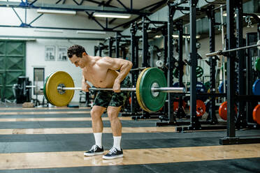 Muskulöser Mann hebt Gewichte im Fitnessstudio - KVF00178
