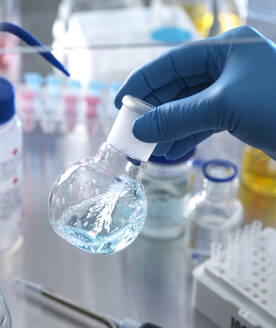 Männlicher Wissenschaftler hält einen Kolben mit einer chemischen Formel unter einem Abzug in einem Labor - ABRF00839