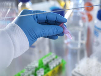 Male scientist holding vial containing chemical formula ready for analysis in laboratory - ABRF00841