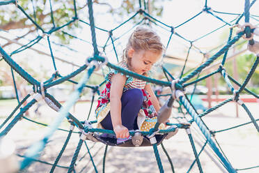 Young blonde girl playing at a public playground on a sunny day. - CAVF93588