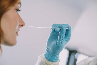 Close-up of patient giving nasal swab in examination room during COVID-19 - MFF07390