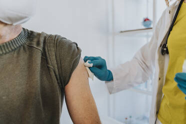 Arzt reinigt den Arm eines Patienten bei der Vorbereitung auf eine Impfung im Untersuchungsraum - MFF07428