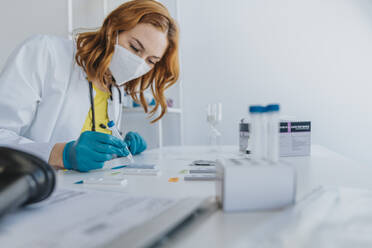 Mitarbeiter des Gesundheitswesens bei der Überprüfung von Proben auf Testkassetten im Untersuchungsraum - MFF07448