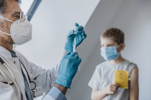 Arzt bei der Vorbereitung der COVID-19-Dosis für den Patienten im Hintergrund in der Klinik - MFF07483