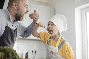 Vater und Tochter beim Essen in der Küche zu Hause - KMKF01566