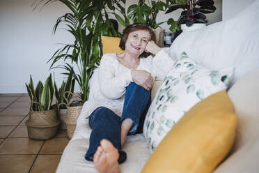 Senior woman relaxing on sofa at home - EBBF02569