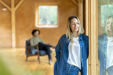 Young woman wearing denim looking away while standing with man in background at spacious room - SBOF02802