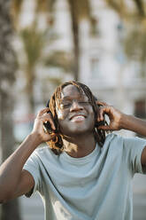 Happy man listening music through headphones - GMCF00019