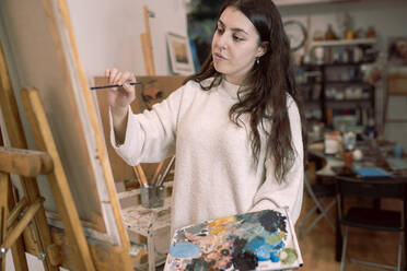 Weibliche Künstlerin malt auf Leinwand in einem Kunstatelier - JCCMF01293