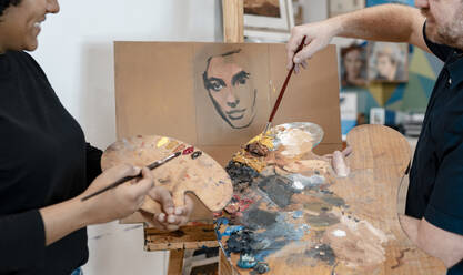 Männlicher Künstler unterrichtet eine Malerin im Malen - JCCMF01300