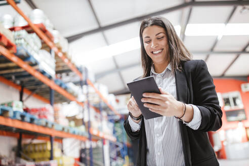 Smiling female manager using digital tablet in illuminated distribution warehouse - LJF02089