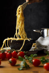 Spaghetti im Sieb um Kirschtomaten auf dem Tisch - IFRF00417