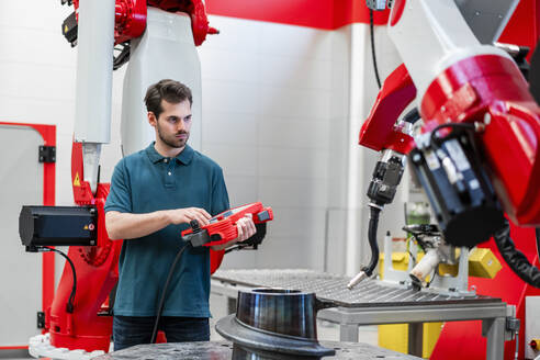 Männlicher Ingenieur, der die Steuerung einer Maschine in einer Fabrik bedient - DIGF14565