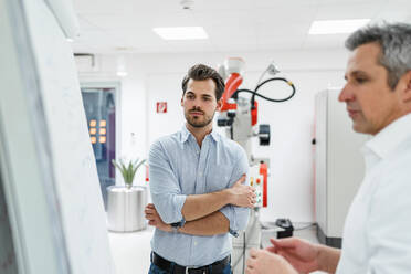 Männliche Unternehmer schauen auf eine weiße Tafel in einer Fabrik - DIGF14590