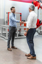 Smiling automation engineers shaking hands in industry - DIGF14660