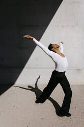 Flexible man practicing dance against wall - TCEF01576