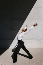 Male dancer practicing against wall on sunny day - TCEF01578