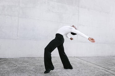 Male dancer practicing urban dance against white wall - TCEF01584