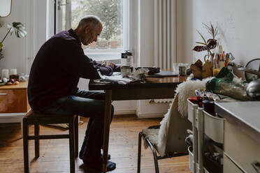 Emotionally stressed man at table in living room - MASF21961