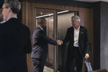 Älterer Geschäftsmann schüttelt Hände mit männlichem Fachmann im Sitzungssaal während einer Sitzung - MASF21978