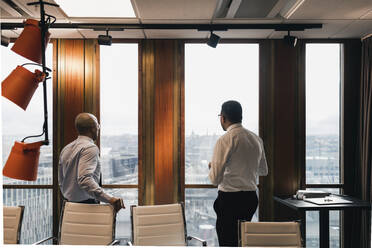 Männliche Unternehmer blicken durch das Fenster, während sie im Sitzungssaal eine Strategie planen - MASF22015