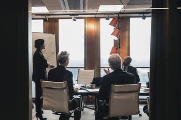 Business colleagues planning strategy during meeting in board room at office - MASF22037