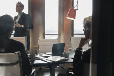 Männliche und weibliche Kollegen hören einer Geschäftsfrau zu, die während einer Sitzung im Sitzungssaal die Strategie erläutert - MASF22038