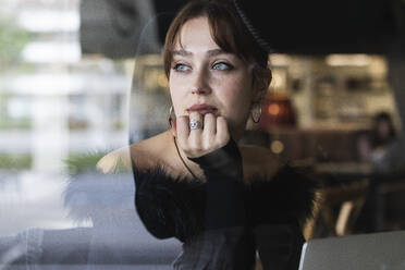 Beautiful businesswoman with blue eyes looking though window at cafe - PNAF00863