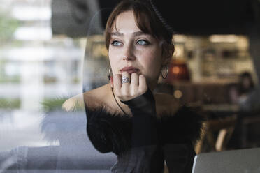 Schöne Geschäftsfrau mit blauen Augen, die durch das Fenster eines Cafés schaut - PNAF00863