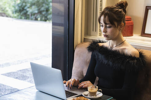Geschäftsfrau arbeitet am Laptop, während sie in einem Café sitzt - PNAF00866