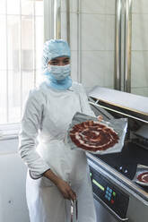 Angestellter hält ein Fleischpaket in einer Fabrik - JAQF00319