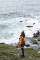 Junge Frau steht auf einem Felsen am Meer - JAQF00336