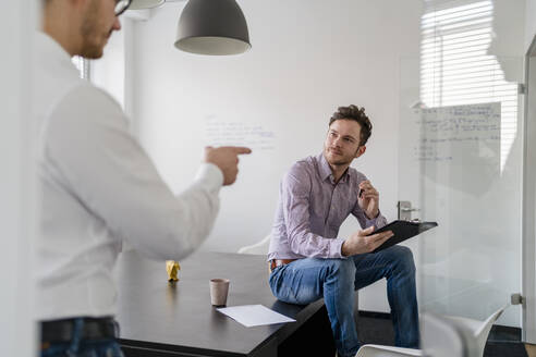 Männlicher Unternehmer plant mit einem Kollegen während einer Besprechung im Büro - DIGF14685