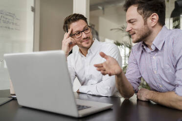 Geschäftsmann mit männlichem Kollegen diskutiert über Laptop im Büro - DIGF14701
