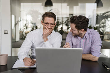Geschäftsleute, die während einer Besprechung im Büro über einen Laptop diskutieren - DIGF14702