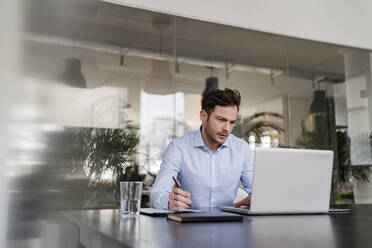 Männlicher Unternehmer arbeitet am Laptop am Schreibtisch im Büro - DIGF14704