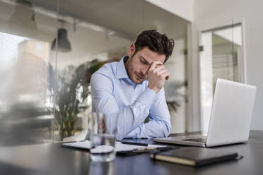 Müder Geschäftsmann am Schreibtisch im Büro - DIGF14707